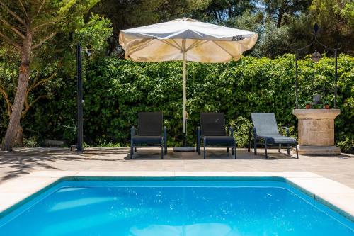 a swimming pool with two chairs and an umbrella at Pomeres Nou in Sa Coma