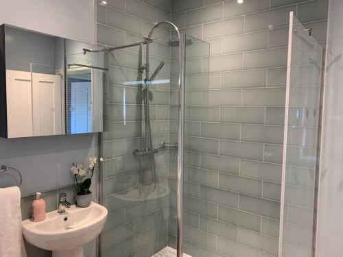 a bathroom with a shower and a sink and a mirror at Nina's Cottage - Southwold in Southwold