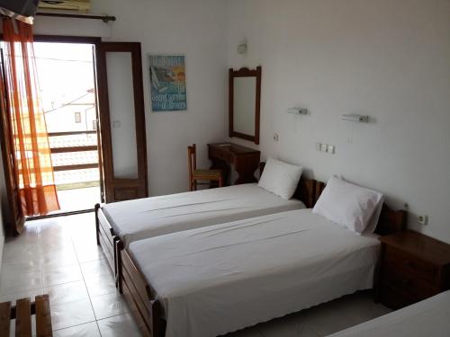 1 dormitorio con 2 camas, espejo y ventana en Hotel Hellinikon, en Ouranoupoli