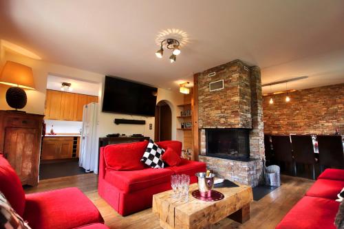 sala de estar con muebles de color rojo y chimenea de ladrillo en Ski-in/Ski-out Chalet, Quiet Location, and Jacuzzi, en Vars