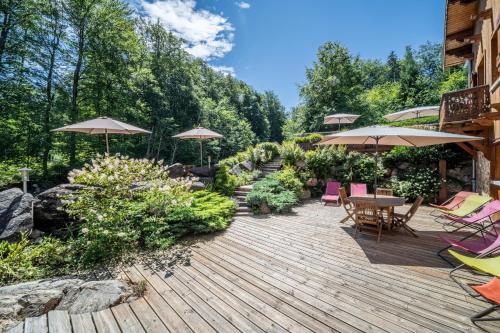 a wooden deck with chairs and tables and umbrellas at Au Rêve Savoyard 7 - 4 personnes in Morillon