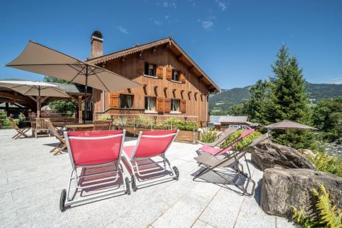 a group of chairs and umbrellas in front of a house at Au Rêve Savoyard 7 - 4 personnes in Morillon