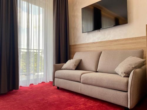 a living room with a couch and a large window at Hotel am Waldkasino in Erfurt