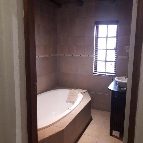 a bathroom with a bath tub and a sink at Whispering Pines Country Estate in Magaliesburg