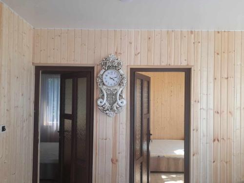 um relógio pendurado numa parede ao lado de duas portas em Mariam's Cottage em Kobuleti