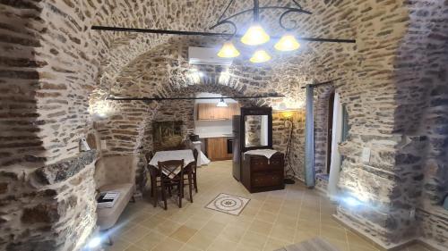a room with a stone wall with a table and chairs at Olympus in Olýmpoi
