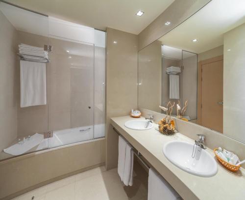 a bathroom with two sinks and a tub and a mirror at Hotel Reston Valdemoro in Valdemoro