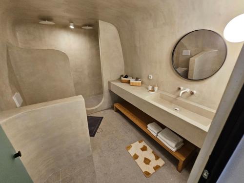 Petroma Cave Suites في Vourvoúlos: حمام مع حوض ومرآة