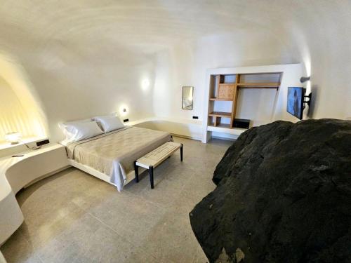 um quarto com uma cama e um banco em Petroma Cave Suites em Vourvoúlos