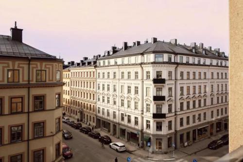 a large white building with cars parked in a parking lot at Cosy Apartment in heart of Stockholm Sweden in Stockholm