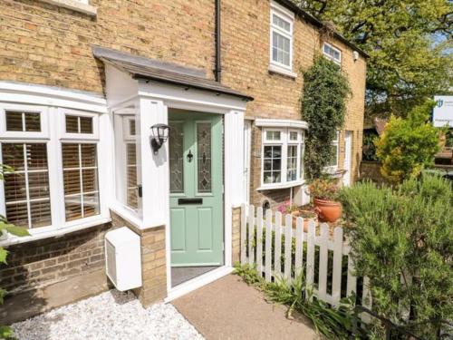 uma casa de tijolos com uma porta verde e uma cerca branca em Minster Cottage - Cathedral Quarter with Permit Parking em Lincoln