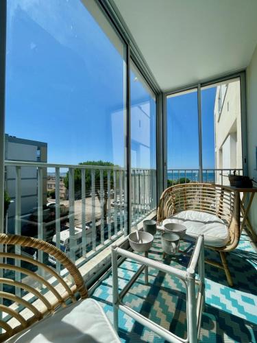 un balcon avec une chaise en rotin et une table sur un balcon dans l'établissement Le Neptune Appartement T2 tout confort au calme et à deux pas de la plage, au Grau-du-Roi