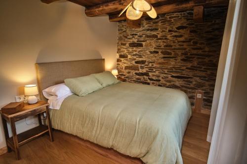 a bedroom with a bed and a brick wall at Lar da cima in Folgoso
