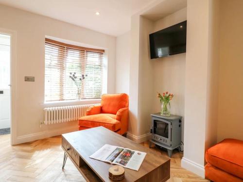 a living room with an orange chair and a table at Minster Cottage - Cathedral Quarter with Permit Parking in Lincoln