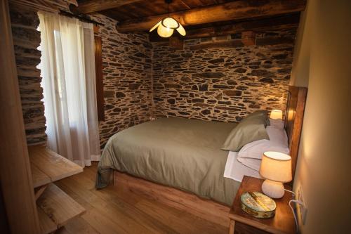 a bedroom with a bed and a brick wall at Lar da cima in Folgoso