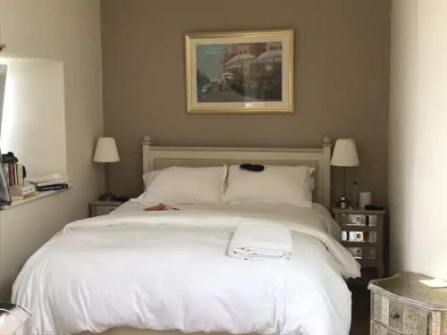 1 dormitorio con 1 cama blanca grande y 2 lámparas en 3 Quay Cottage Killala. Luxury Sea-Front Cottage, en Killala