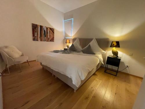 um quarto com uma grande cama branca e uma cadeira em Luxuriöses Loft mit großer Sonnenterrasse & Sauna em Munique