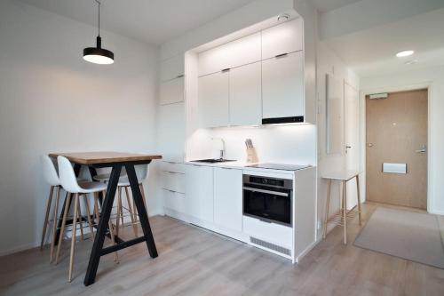 a kitchen with white cabinets and a wooden table at Norden Homes 2-Bedroom Apartment in Turku