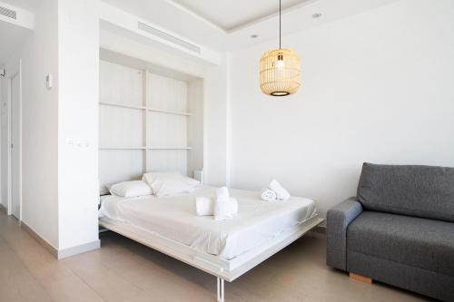 Un dormitorio blanco con una cama y una silla. en Santa Clara, en Torremolinos