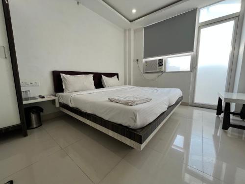 a white bedroom with a large bed and a window at Hotel Shree A unit of THC Group in Kota