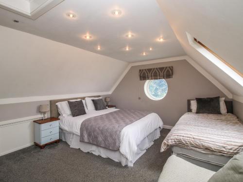 a attic bedroom with two beds and a window at The Coach House in Whitmore
