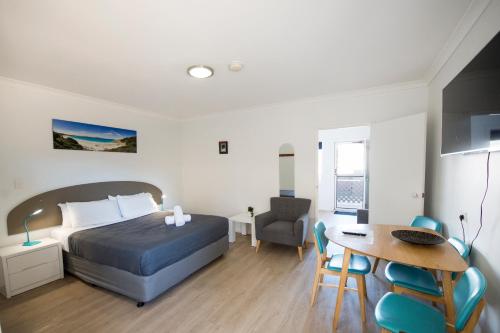 a bedroom with a bed and a table and a desk at Clearwater Motel Apartments in Esperance