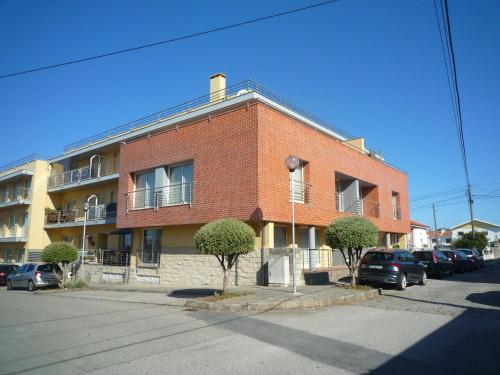 a red brick building with cars parked in a parking lot at Casa da Vinha in Viana do Castelo