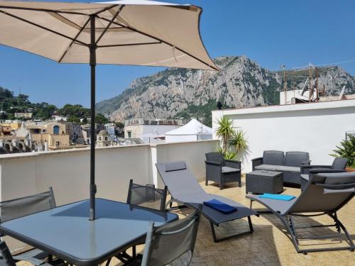 eine Terrasse mit einem Tisch, Stühlen und einem Sonnenschirm in der Unterkunft Romy Blu in Capri