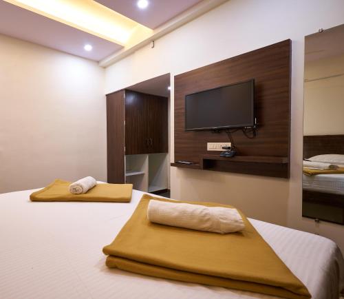コールハープルにあるHotel Ranjan Deluxeのベッドルーム1室(ベッド1台、薄型テレビ付)