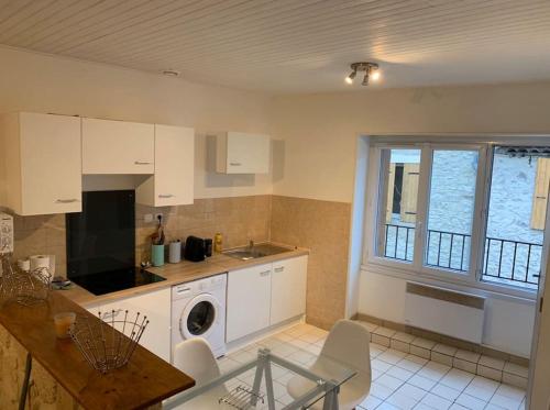 eine Küche mit weißen Schränken, einem Waschbecken und einem Fenster in der Unterkunft Jolie T3 / Emplacement Ideal in Le Pouzin