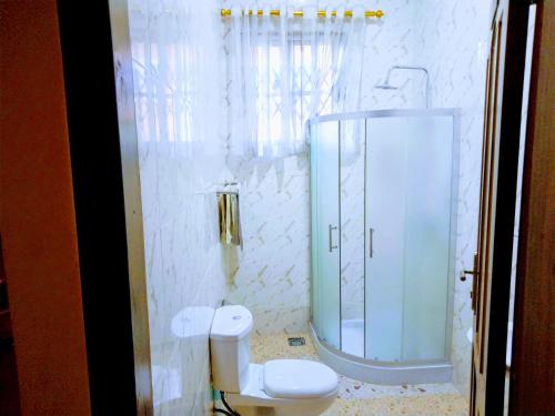 a bathroom with a toilet and a glass shower at Room in Apartment - Renajoe Ejisu-Kubease in Kubeasi