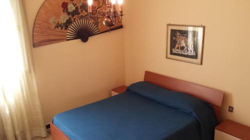 een kleine slaapkamer met een blauw bed en een kroonluchter bij B&b A Casa Tua in Civitanova Marche