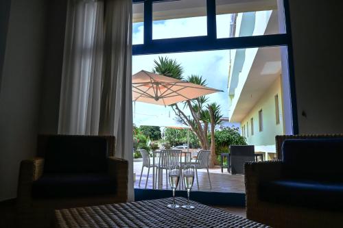 eine Terrasse mit einem Sonnenschirm, einem Tisch und Stühlen in der Unterkunft Hotel Baia Turchese in Lampedusa