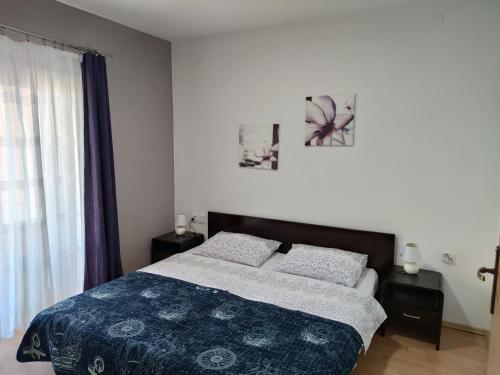 una camera da letto con un letto con una coperta blu e una finestra di Apartments Dijana a Krk