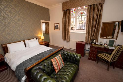 une chambre d'hôtel avec un lit et un canapé en cuir dans l'établissement Castle and Ball by Greene King Inns, à Marlborough