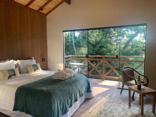 um quarto com uma cama e uma grande janela em Canto da Floresta em Monte Verde