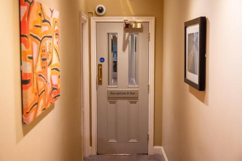 une porte blanche dans un couloir avec des peintures murales dans l'établissement Castle and Ball by Greene King Inns, à Marlborough