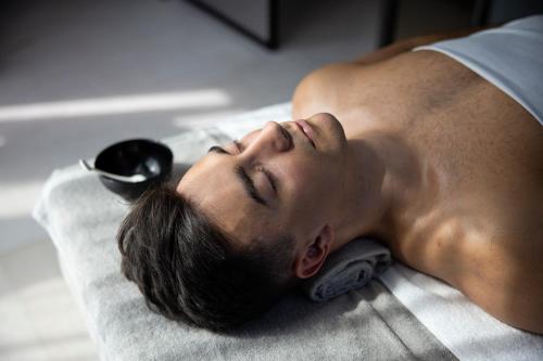 a man laying on a bed with a hair brush at Hotel Riviera in Moss