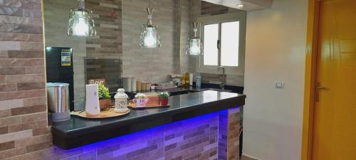 eine Küche mit einer Theke mit lilafarbenen Leuchten in der Unterkunft Relax view apartment in Madinat as-Sadis min Uktubar