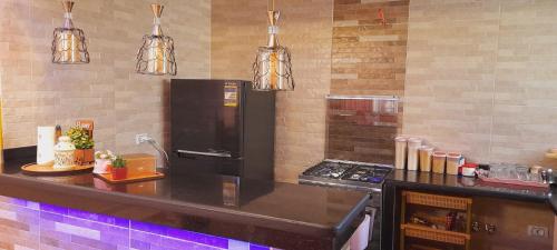 eine Küche mit einer Theke mit einem Kühlschrank und Lampen in der Unterkunft Relax view apartment in Madinat as-Sadis min Uktubar