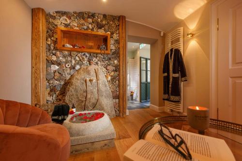 a living room with a stone wall with a shower at Luxus Hotel Design Villa Ottilienruh Ilsenburg im Harz in Ilsenburg