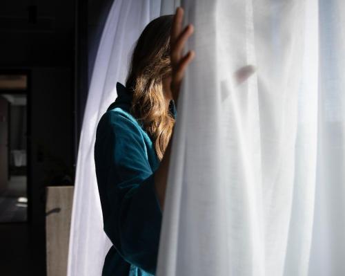 a woman is looking out of a white curtain at Hotel Riviera in Moss