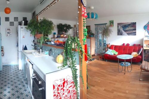 uma cozinha e uma sala de estar com um sofá vermelho em Charmant 2 pièces, parking privé em Bagnolet