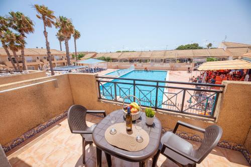 a balcony with a table and chairs and a pool at Destinos De Sol Los Alcazares - Montepío Minería in Los Alcázares