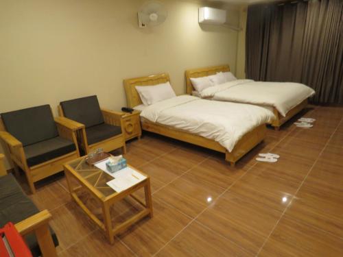 2 Betten und ein Stuhl in einem Zimmer in der Unterkunft Legendary Hotel Chitral in Chitral