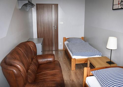 a living room with a leather couch and a bed at Hostel Sadowianka in Ostrów Wielkopolski