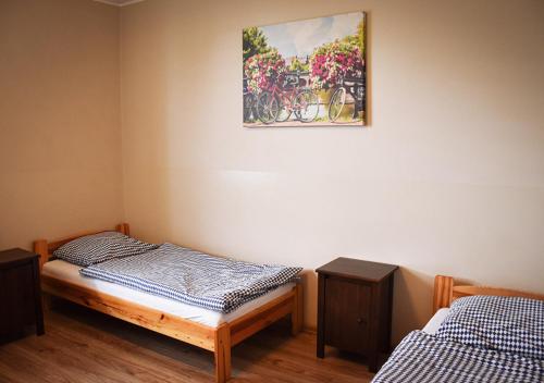 a room with two beds and a picture on the wall at Hostel Sadowianka in Ostrów Wielkopolski