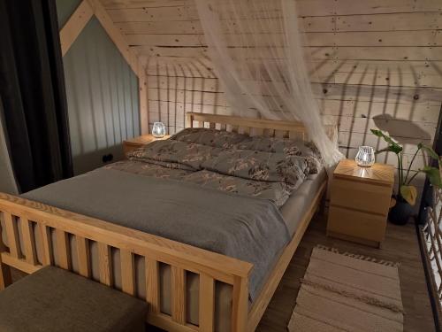 a bedroom with a wooden bed with a mosquito net at Mazury Holiday Cottage in Piecki