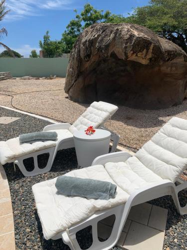 zwei weiße Sessel vor einem Felsen in der Unterkunft 2 Bedrooms - Rock Palma Apartments in Noord