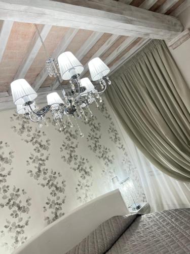 a bedroom with a bed and a chandelier at L’ Aia del Principe in Montepulciano